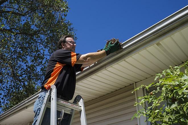 fixing a broken gutter to prevent water buildup in Hales Corners, WI