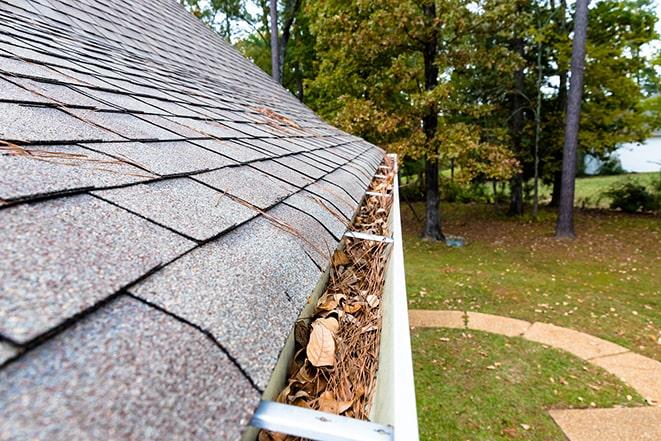 a close-up of a clogged gutter being cleared